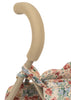 Close-up of the beige curved handle on the metal frame of the Konges Sloejd Doll Stroller - Vienna, highlighted by floral-patterned fabric in red, blue, and green flowers and leaves draped below.
