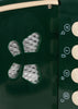 Close-up of a green Konges Sloejd Accordian featuring four silver-mesh sound holes in a butterfly pattern and a vertical row of cream-colored buttons labeled with lowercase letters.