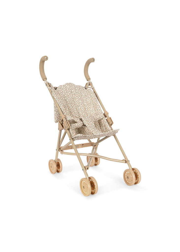 Konges Sloejd Doll Stroller - Milk Tank features a lightweight metal frame with curved handles and a fabric seat adorned with a small brown and white spotted pattern. This beige toy stroller has eight small tan double wheels for smooth movement and is shown empty.