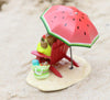 A Wee Forest Folk Tiny Collectible - Perfect Beach Day! features a hand sculpted mouse on a red chair under a watermelon-patterned umbrella with a striped beach bag, all set on light sand.