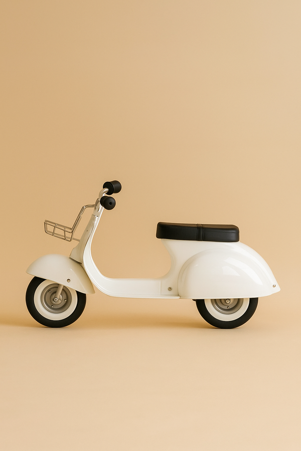 The PRIMO Ride On Kids Toy Classic, a white retro-style scooter with black seat and grips, is parked on a beige background. Its minimalist look, front basket, and classic rounded shape make it an ideal gift for children.
