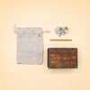Flat lay featuring the Goat Cake Topper - Final Sale, displayed alongside a star-patterned drawstring pouch, a sheep-shaped candle holder with two candles, a beige taper candle, and a rustic wooden box adorned with the “camplollow” logo—perfect for adding a handcrafted touch to birthday celebrations or as a unique collectible keepsake.