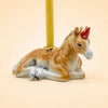 A charming keepsake, the Horse Cake Topper features a handcrafted design resembling a resting horse with gold accents, set against a light beige background.