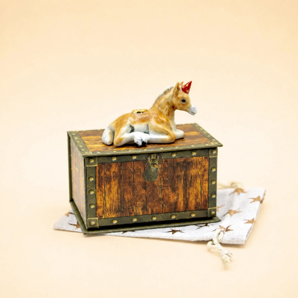 A Horse Cake Topper, offered as a final sale item, rests atop a small wooden chest with gold accents and a brass lock, which sits on a star-patterned cloth.