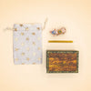 A star-patterned drawstring bag, a Pig Cake Topper - Final Sale—featuring a small pig figurine with two rings that’s perfect as a handcrafted collectible or keepsake birthday decoration—a yellow stick, and a wooden box labeled “Camp Hollow” are arranged on a light beige surface.
