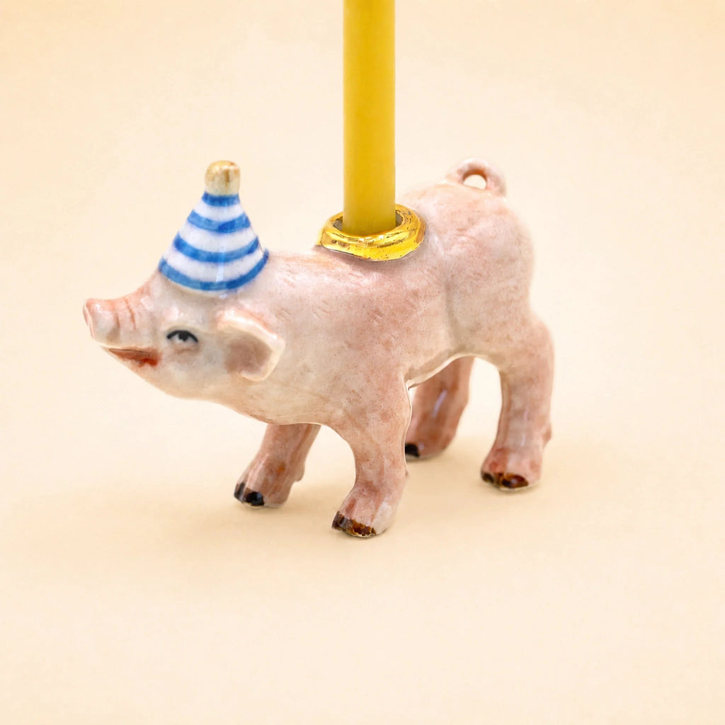 Add a touch of whimsy to any celebration with the Pig Cake Topper – Final Sale. This charming handcrafted collectible features a small pig wearing a blue and white striped party hat and carrying a yellow candle on its back, set against a plain beige background. Perfect as a keepsake birthday decoration!.