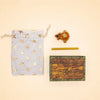 A drawstring bag adorned with gold stars, a small wooden “camp hollow” box—a charming keepsake treasure chest—a golden stick, and the Bunny Rabbit Cake Topper collectible figurine are arranged on a beige background.