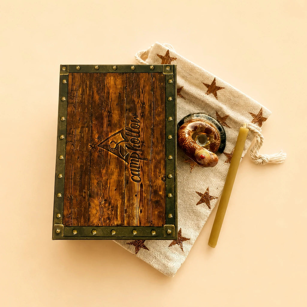 A Snake Cake Topper - Final Sale is displayed on a star-patterned cloth beside a golden straw, a beeswax birthday candle, and two spiral seashells—all arranged against a beige background.