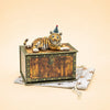 A “Tiger Cake Topper - Final Sale,” a small handcrafted collectible figurine of a tiger wearing a party hat, rests atop a decorative wooden keepsake treasure chest placed on a star-patterned cloth against a beige background.