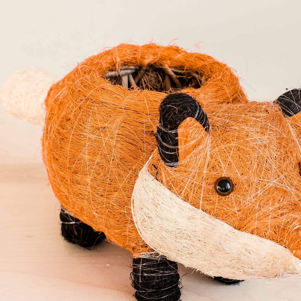 A close-up of a whimsical Animal Planter - Fox shaped like a brown and beige pig, made from wound and textured fibers, featuring button eyes and distinct black thread details on its body. This item is part