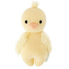 A soft, hand-knit plush toy resembling a Cuddle + Kind Baby Duckling with a fluffy body, standing against a white background. It has a tuft of hair on top and a smiling face.