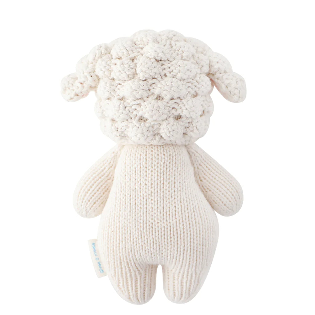 A Cuddle + Kind Baby Lamb, hand-knit from Peruvian cotton yarn, with a textured curly fleece head and smooth body in neutral white tones, pictured against a white background.