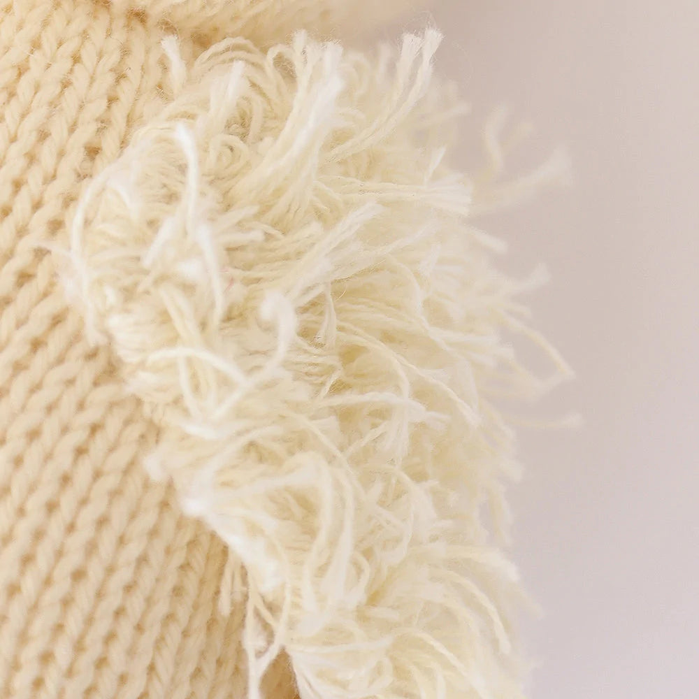 Close-up view of a Cuddle + Kind Baby Duckling hand-knit fabric with frayed edges and visible fluffy threads, highlighting its texture.