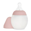 A Medical Grade Silicone Baby Bottle with a translucent body and measurements marked, topped with an anti-colic silicone teat. It features a soft pink screw-on lid and base, isolated on a white background.
