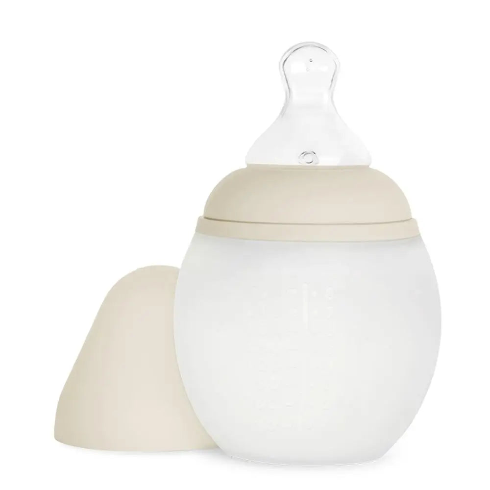 A Medical Grade Silicone Baby Bottle with a beige cap to the side, featuring a translucent nipple on top, isolated on a white background.