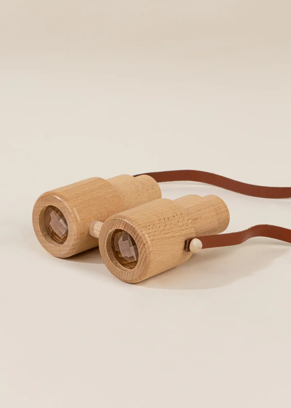 A pair of Wooden Binoculars for toddlers with a brown leather strap, set against a light beige background.