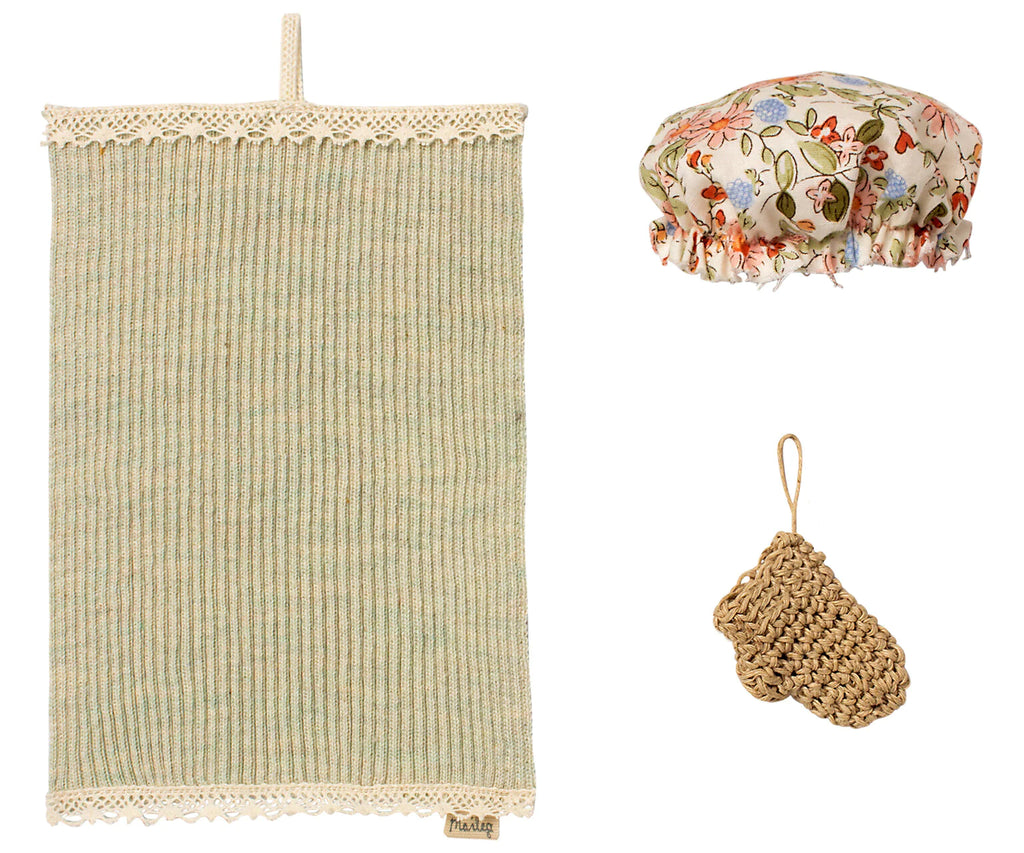 Three isolated items on a white background: a Maileg Wellness Set with fringe, a floral fabric-covered bowl, and a small knitted brown scrubbing pad.