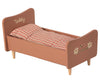 A small, toddler-sized Wooden Bed for Teddy Mum - Rose with "Teddy mom" engraved on the headboard, featuring a checkered orange and white bedding and a floral design on the foot.