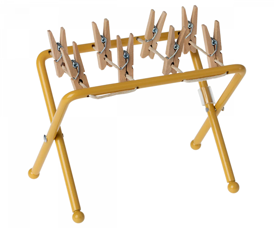 A yellow Maileg Drying Rack, Mouse Size is displayed with multiple small wooden pegs attached along the top bar. The pegs are evenly spaced and ready for use, while the rack stands on four rounded legs.