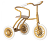 A Maileg Tricycle With Basket with a golden-brown frame, featuring three white-spoked wheels with white tires. The handlebars and seat back are padded with white material, and the wooden seat is perfect for young riders. This charming tricycle exudes a classic, nostalgic look.