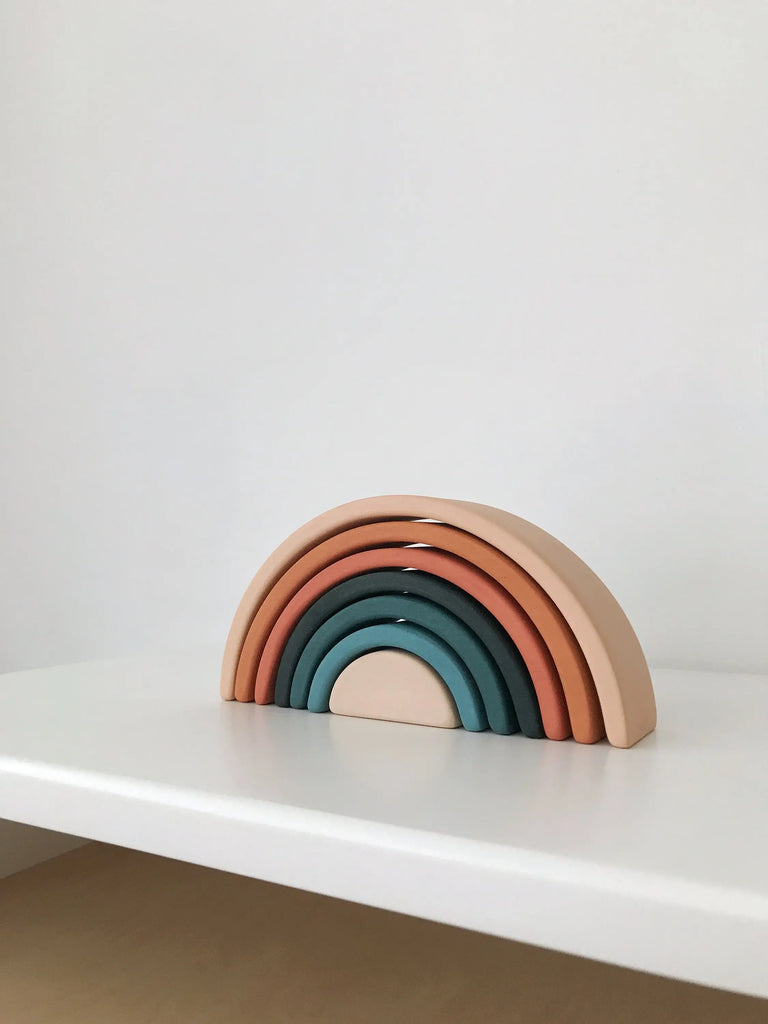 A set of Handmade Mini Rainbow Stackers - Tropics in gradient shades from teal to peach, neatly stacked in ascending order, displayed on a white shelf against a white background.