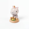 A Wooden Unicorn Bobblehead sitting on a base, with a neutral gray body, golden hooves, and a pink and gold horn, surrounded by small wooden flowers.
