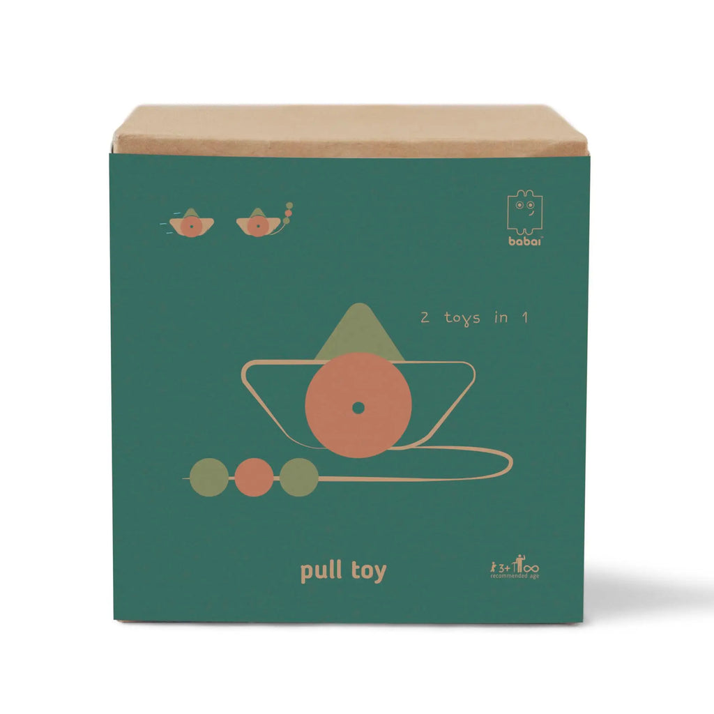 A teal-colored toy box featuring a minimalist design of a Handmade Wooden Boat Pull Toy with planets and stars, labeled "2 toys in 1" and "pull toy" with the babai toys logo, handmade in