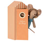 A small Maileg Beach Mouse - Mom wearing a floral sun hat and blue outfit peeks out from an orange and white striped beach cabin-shaped box. The box has a round window and the words "Cabine de Plage" written on it, perfect for vacation time at your cozy beach house.