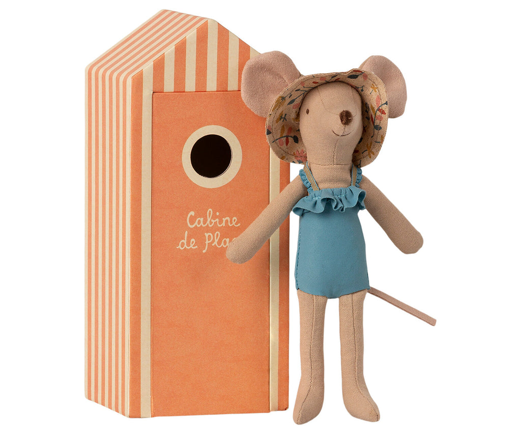 A Maileg Beach Mouse - Mom wearing a blue swimsuit and a floral sun hat stands next to an orange striped beach house with a circular window and the French text "Cabine de Plage" on it. It's clearly vacation time!