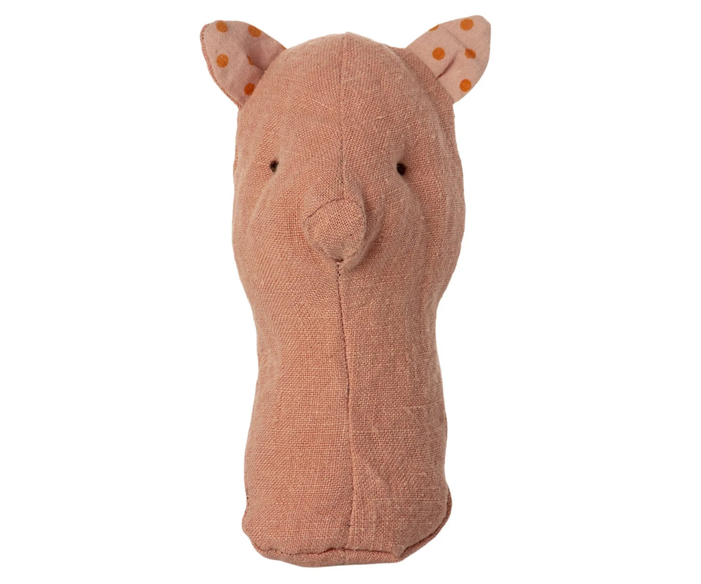 A soft, peach-colored fabric toy shaped like an animal head with pointed ears featuring orange polka dots. This charming Maileg Lullaby Friend Rattles, Pig has minimalistic, stitched facial features, including small black eyes and a simple nose. Perfectly presented in a gift box, it makes an ideal present for little ones.