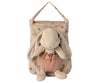 A Maileg Bunny Holly in a peach outfit labeled "bunny hug" resting in a polka dot bag, isolated on a white background.