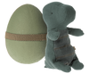 A Maileg Small Gantosaurus in egg - Green, sitting position, leaning against a large green egg wrapped with a burlap ribbon. The elephant is made of textured, dark green fabric with visible stitching and is hugg