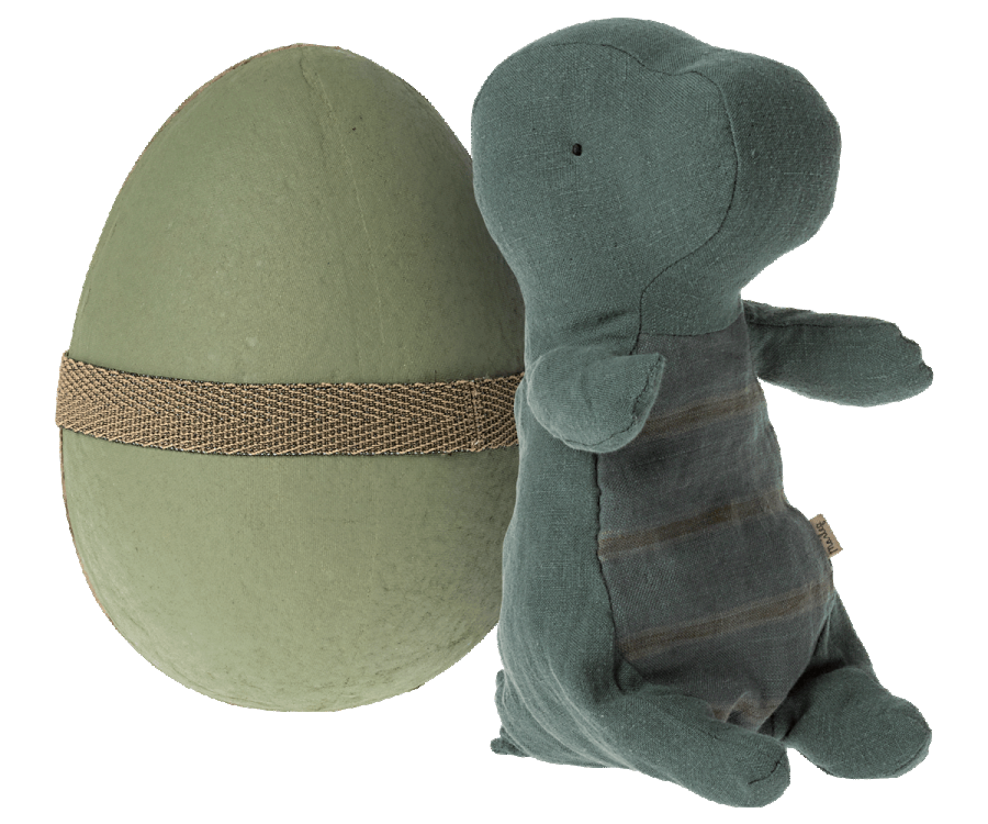 A Maileg Small Gantosaurus in egg - Green, sitting position, leaning against a large green egg wrapped with a burlap ribbon. The elephant is made of textured, dark green fabric with visible stitching and is hugg