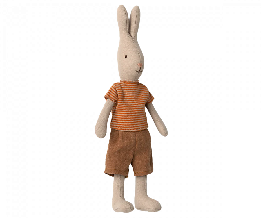 A Maileg Rabbit Size 1 - Classic T-shirt & Shorts standing upright, dressed in a striped orange and yellow shirt and brown shorts. The bunny, made from natural linen, has long ears, a small black nose, and stitched facial features, giving it a cute and friendly appearance.