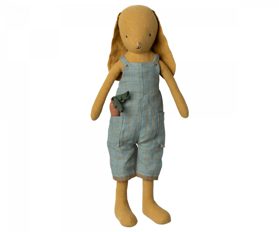 A soft, Maileg Bunny Size 3, Dusty Yellow doll wearing a plaid blue and beige jumpsuit from its charming Bunny/Rabbit 3 wardrobe, standing upright with long ears and holding a small toy camera.