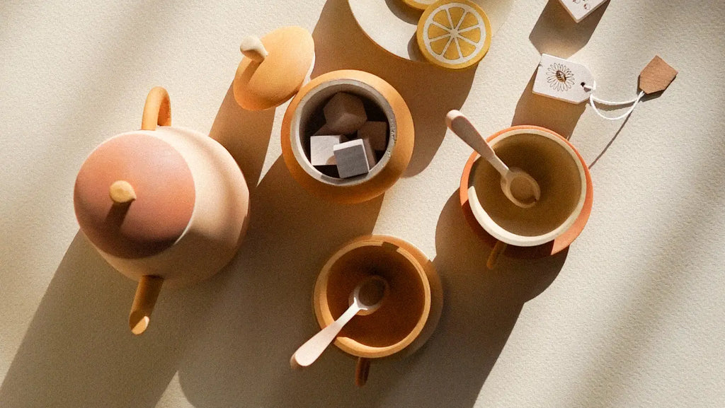 Overhead view of a neatly arranged Handmade Wooden Tea Set - Flower with a teapot, cups, and lemon slices, all cast in warm sunlight creating soft shadows on a textured surface.