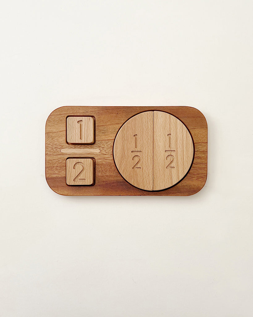 A Wooden Fraction Puzzle - Made in USA designed as a fraction puzzle, featuring pieces marked "1/2 + 1/2" on a round piece and two small squares on a rectangular base, set against a plain