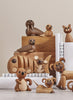 A collection of Spring Copenhagen Wally handmade wooden animal figurines, including beavers, bears, and mice, displayed on steps with rolled-up white papers. These figurines showcase various playful poses and expressions.