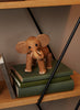 A Spring Copenhagen Ollie - Elephant figurine crafted from FSC Oak with large ears and a trunk sits on a stack of green books on a shelf.