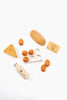 A flat lay image of the Sabo Concept Handmade Wooden Dairy Set on a white background, including eggs, a slice of cheese, a baguette, and containers labeled "milk" and.