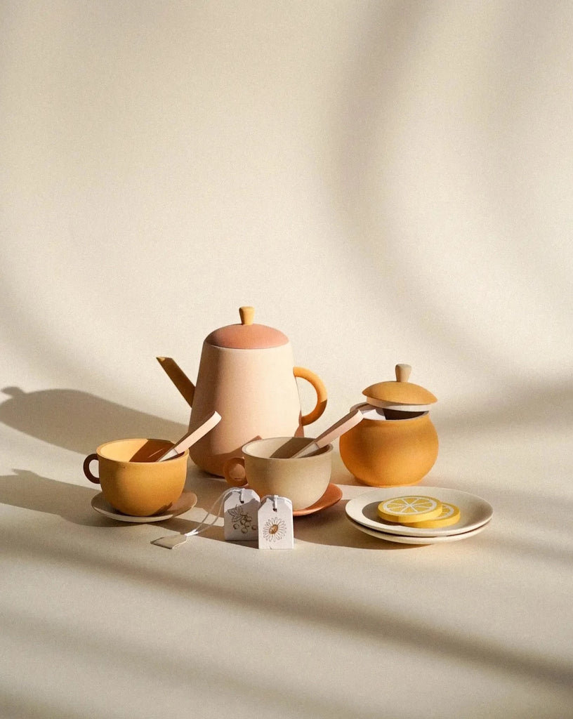 A serene Handmade Wooden Tea Set - Flower arrangement with a teapot, cups, saucers, and a sugar pot in soft beige tones, highlighted by gentle shadows on a neutral background.