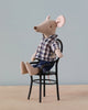 A Maileg Dad Mouse dressed in a plaid shirt and denim pants, sitting relaxed on a miniature black chair against a light blue background.