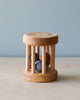 A small handmade wooden rattle crafted from sustainably harvested birch wood, with a circular seat, natural finish, and vertical dowels enclosing colorful balls, placed on a plain background.
