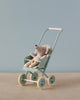 A plush toy mouse dressed in striped clothes sits in a Maileg Miniature Stroller, Micro - Mint against a plain, light blue background.