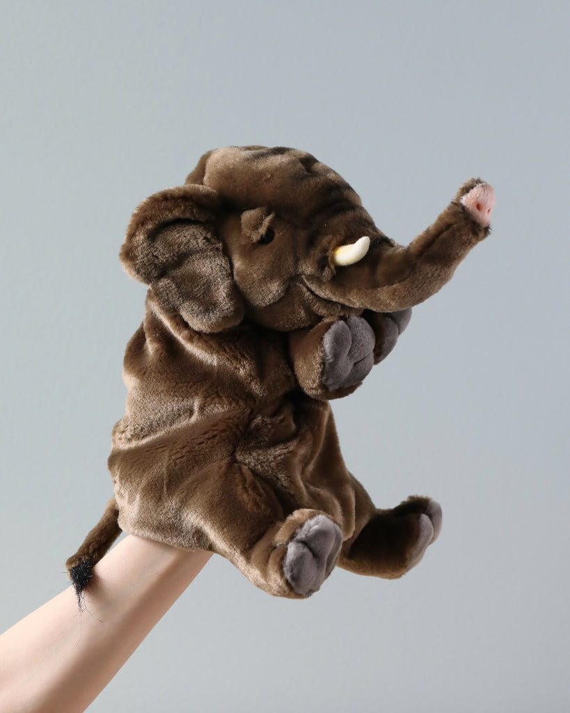A Elephant Puppet made from quality man-made materials, showcased against a plain light grey background. The puppet has prominent tusks and a raised trunk.