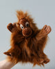 A Orangutan Puppet with fluffy brown fur and a friendly expression, crafted as a realistic plush animal, held up against a light grey background.