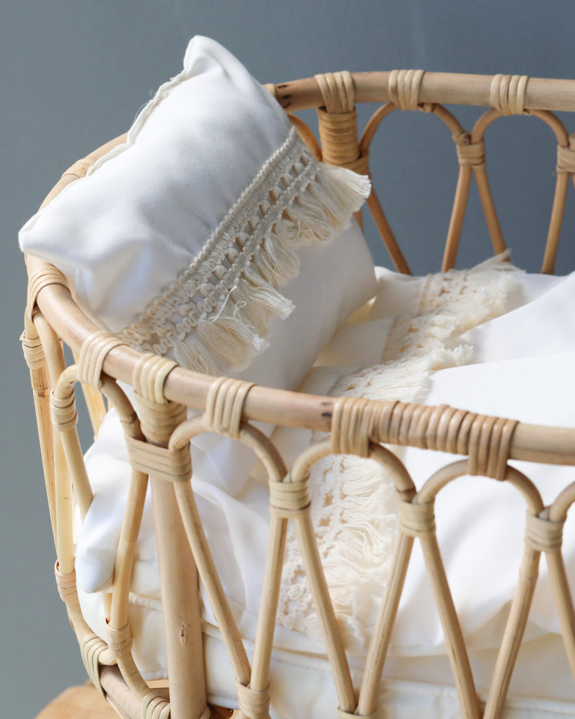 Close-up of a delicate white lace pillow resting on a Poppie Rattan Doll Crib + Duvet Set, highlighting intricate textile details against a soft, neutral background.