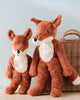 Two Senger Naturwelt Stuffed Animal - Fox toys, one small and one large, standing beside a wicker basket against a light blue background. The toys have a soft brown color with white.