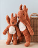 Two Senger Naturwelt Stuffed Animal - Squirrel toys with white bellies standing next to each other, leaning affectionately, handmade in Germany, with a wicker basket in the background, against a soft blue wall.