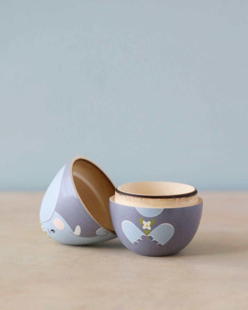 Two Hand Painted Hollow Wooden Easter Eggs - Elephants, one fitting open on its side inside the other on a plain surface against a pale background.